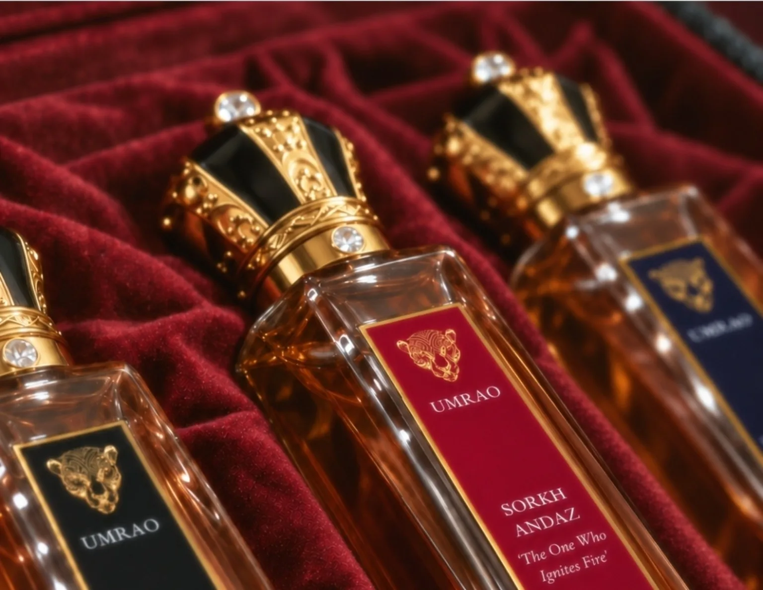 Sorkh Andaz resting on red velvet between two Umrao bottles